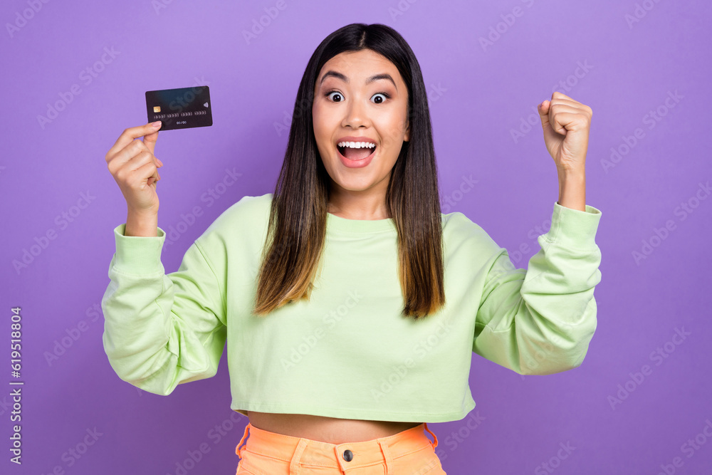 Photo of gorgeous overjoyed impressed woman dressed green clothes hold credit card win jackpot isolated on purple color background