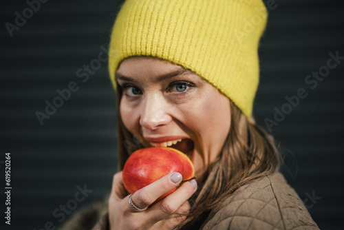 Portrait of young fashionable woman eating apple.