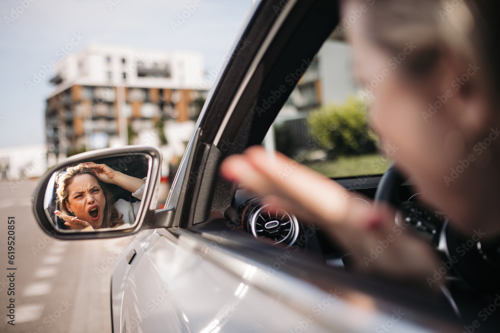 Naklejka premium Nervous woman driving her car in city, shoutng at somebody.