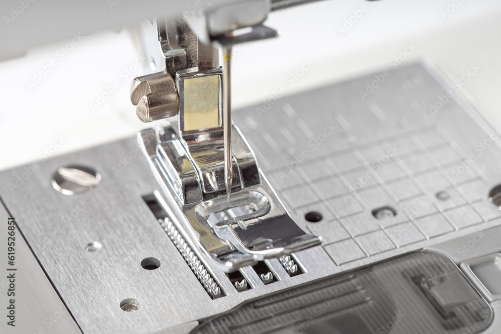 Modern white sewing machine presser foot closeup, macro. Sewing equipment, work tool for atelier business, manufacturing, occupation. Modern white sewing machine presser foot closeup, macro. Sewing equipment, work tool for atelier business, manufacturing, occupation.
