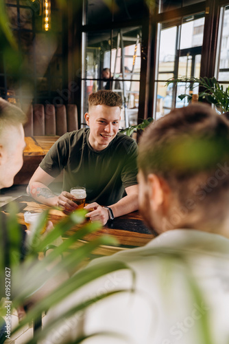 Canvas Print Group of happy relaxing men drinking beer and having talk in pub