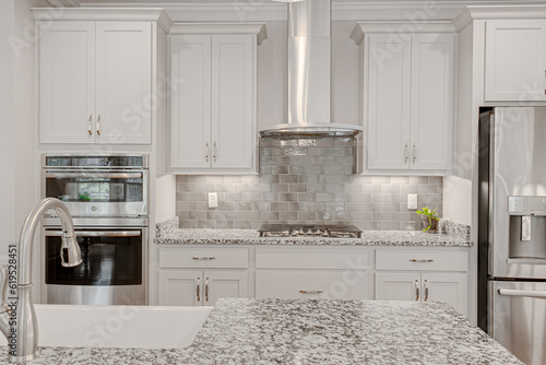 Fotografia Bright white large modern kitchen interior with tiled backsplash marble granite