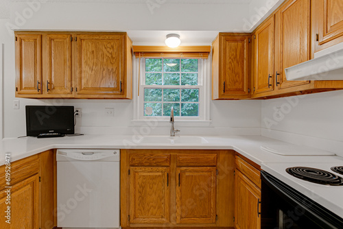 Beautiful modern farmhouse traditional residential kitchen interior with organic wooden cabinets and backyard nature views with marble countertops