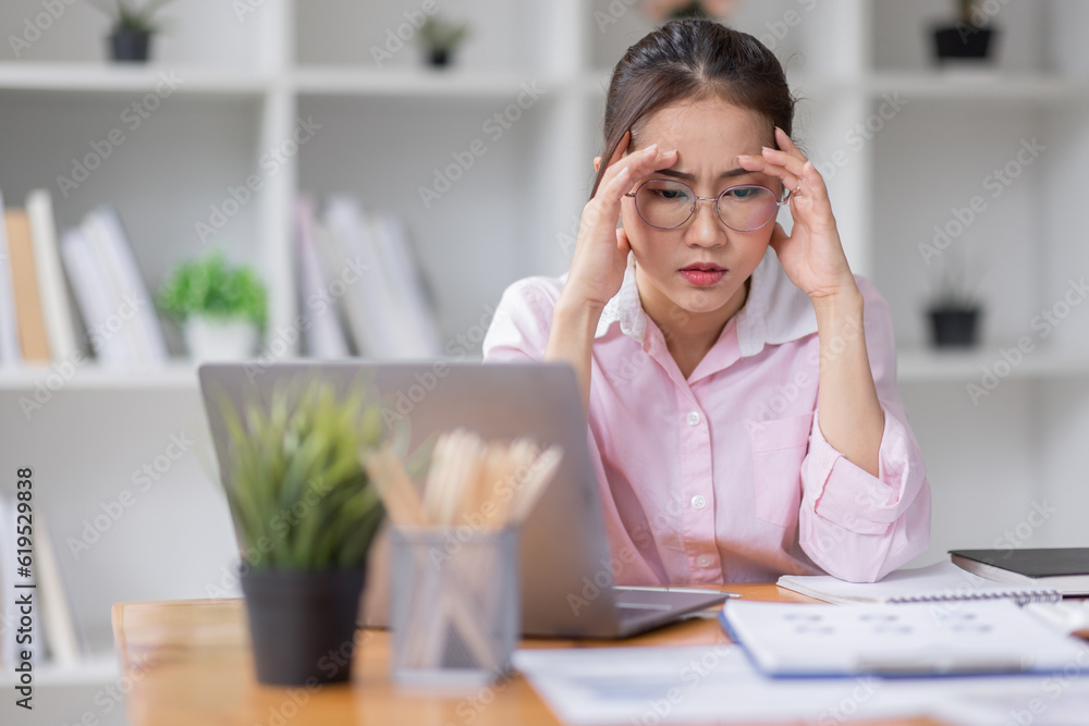 Portrait of tired young business Asian woman wear glasses work with documents tax laptop computer in office. Sad, unhappy, Worried, Depression, or employee life stress concept Portrait of tired young business Asian woman wear glasses work with documents tax laptop computer in office. Sad, unhappy, Worried, Depression, or employee life stress concept