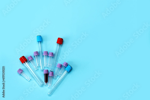 a test tube filled with blood among many empty test tubes on a blue background with copy space.