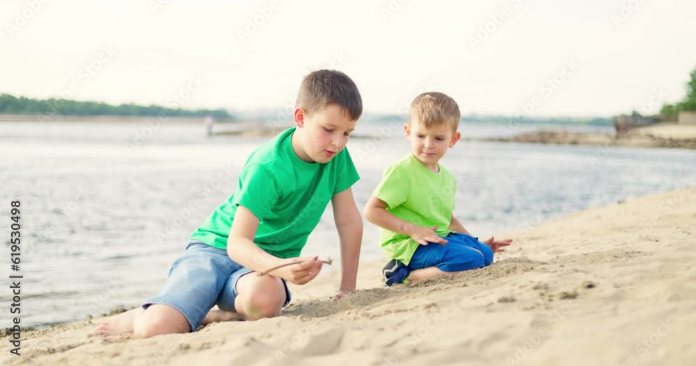 Kids playing with sand on sea beach in warm sunshine in the summer Kids playing with sand on sea beach in warm sunshine in the summer