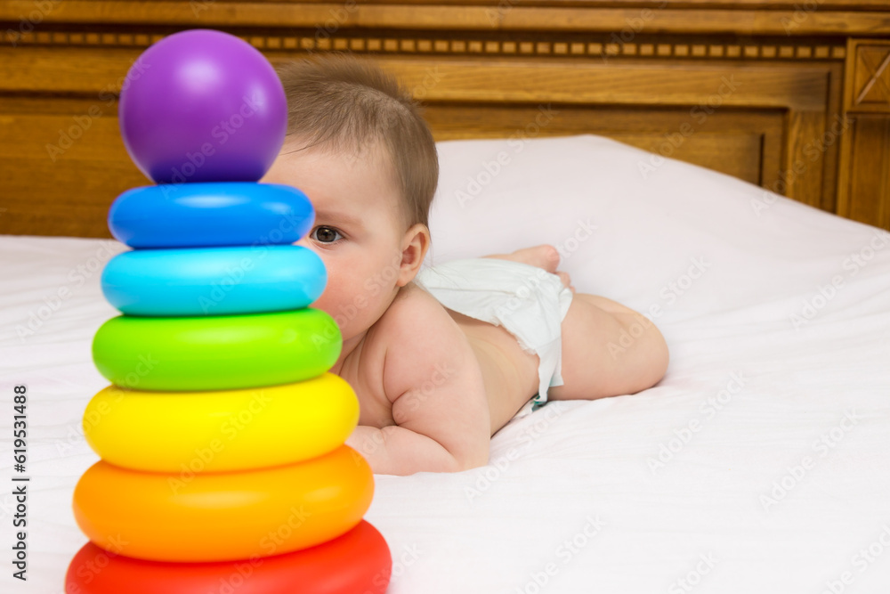 baby girl on her mother's bed behind a multi-colored pyramid baby girl on her mother's bed behind a multi-colored pyramid