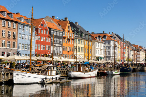 Copenhagen  Denmark - May 20  2023  Scenic view famous colorful house building at Copenhagen Nyhavn harbour canal against blue sky on sunny day. Boats moored at european danish landmark sightseeing