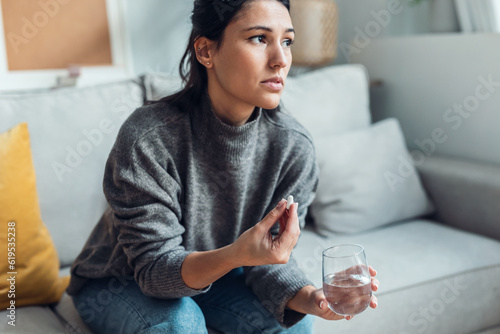 Obraz na płótnie Depressed sad woman taking pills while sitting on couch at home.