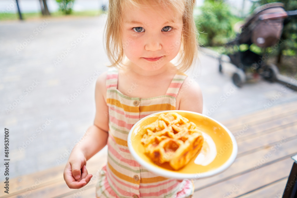Little girl eats Potato waffles, avocado cream with salmon and egg . Healthy breakfast, protein. Restaurant dish. Little girl eats Potato waffles, avocado cream with salmon and egg . Healthy breakfast, protein. Restaurant dish.