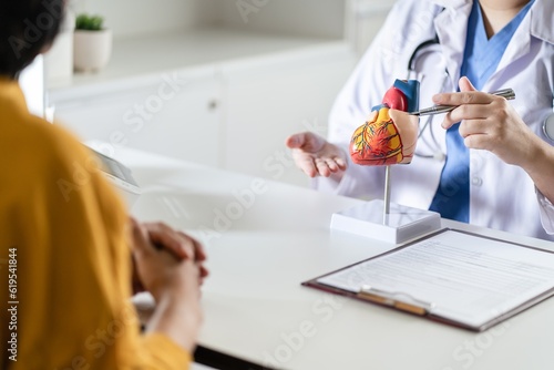 Cardiology Consultation treatment of heart disease. Doctor cardiologist while consultation showing anatomical model of human heart with aged patient talking about heart diseases.
