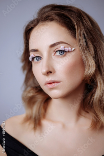 Portrait of a beautiful blondie woman with perfect skin and creative floral makeup look. Gypsophila eye makeup. The concept of cosmetic procedures, femininity, congratulations on women's day.