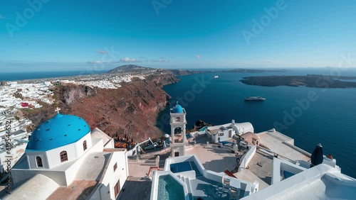 Time lapse of golden hour with view on white and blue church with view on the caldera cliff and cruise ships on the Greek island of Santorini photo