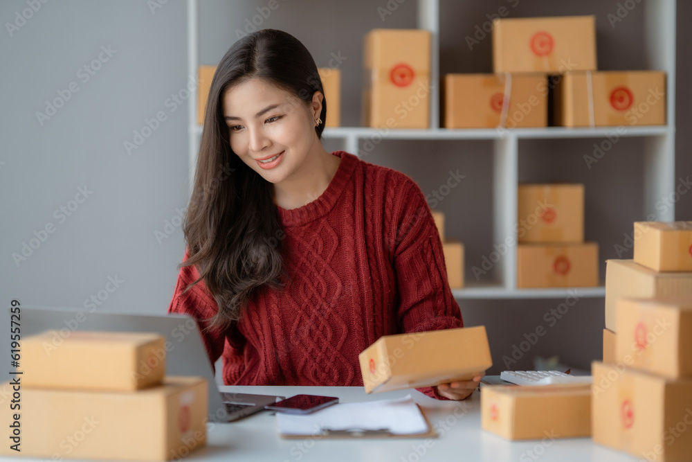 Starting Small business entrepreneur SME freelance, Portrait young woman working at home office, BOX, smartphone, laptop, online, marketing, packaging, delivery, b2b, SME, e-commerce concept.. Starting Small business entrepreneur SME freelance, Portrait young woman working at home office, BOX, smartphone, laptop, online, marketing, packaging, delivery, b2b, SME, e-commerce concept..