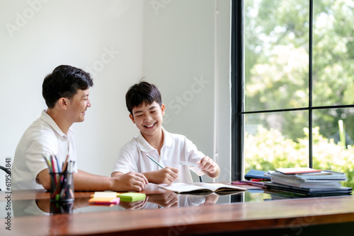 Father helping son doing homework at home..