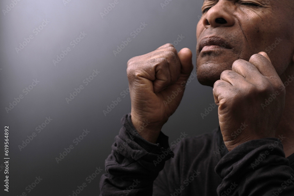 man praying to god with hands together with depression on grey background stock photo	