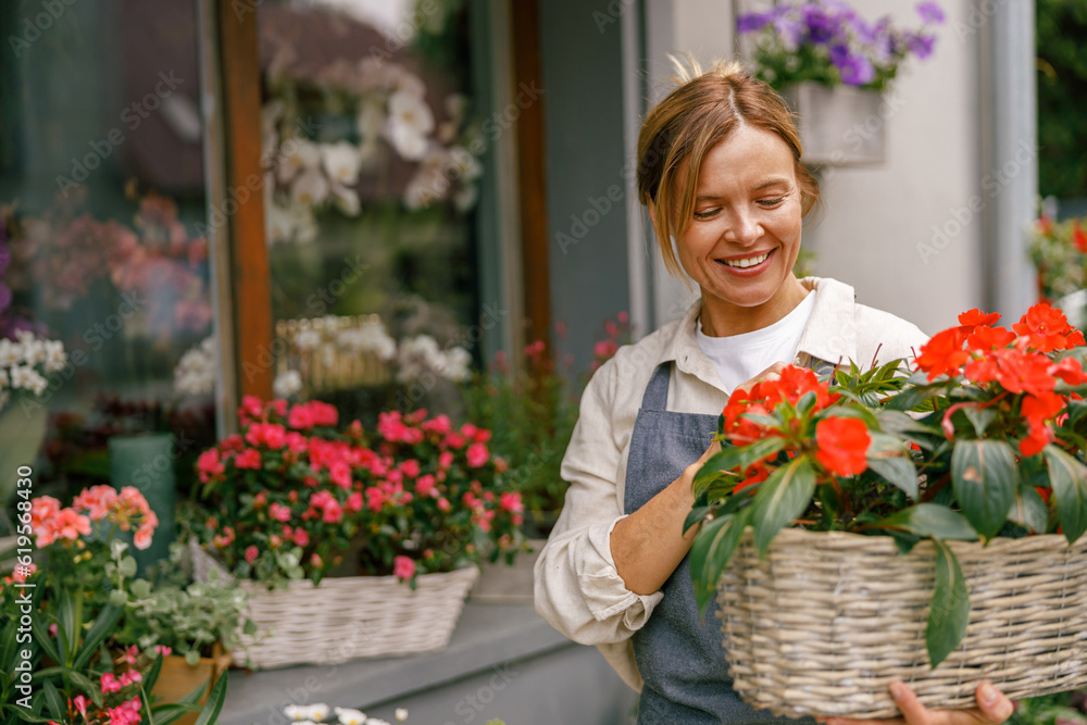 Female florist taking care of houseplant in flower shop. Plant care concept. High quality photo