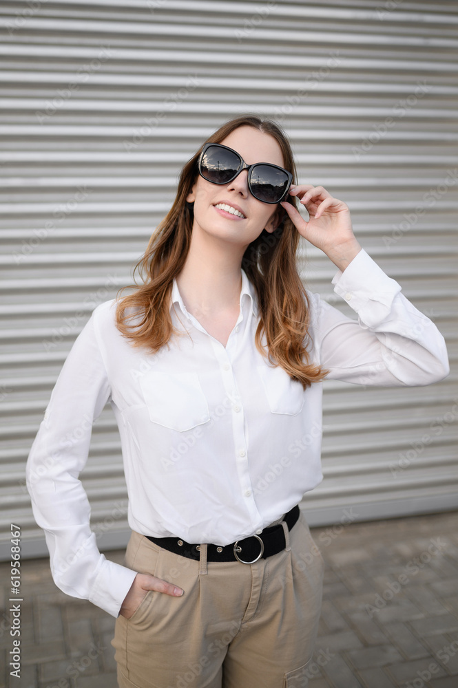 Young woman in summer clothes and sunglasses posing on a gray background.Summer concept, vacation,style and fashion