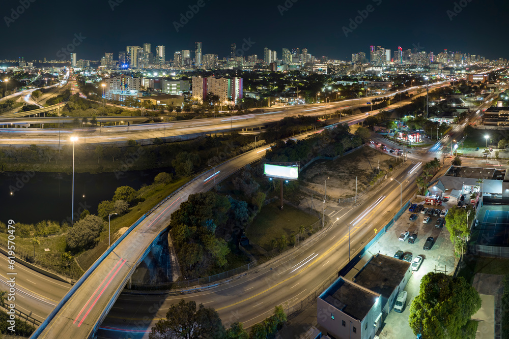 Aerial view of american freeway intersection at night with fast driving cars and trucks in Miami, Florida. View from above of USA transportation infrastructure