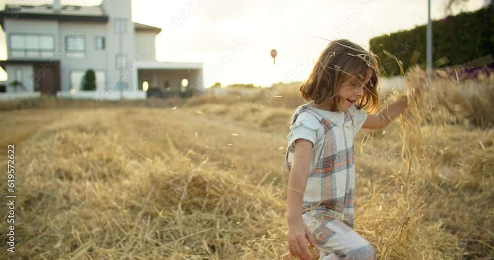 A cheerful Caucasian girl is playing in the hay on the field, scattering it. Happy childhood and happy on the farm. High quality 4k footage A cheerful Caucasian girl is playing in the hay on the field, scattering it. Happy childhood and happy on the farm. High quality 4k footage