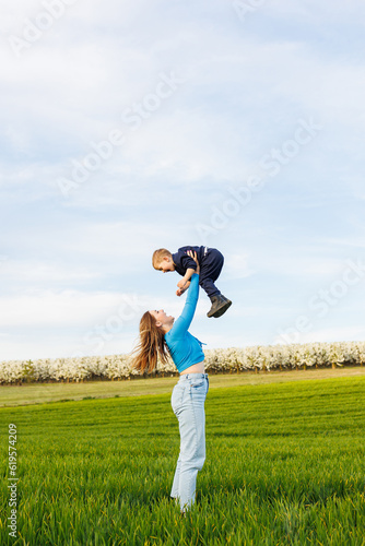 A young mother and her son are lying in the green grass. Family relations of mother and child. A happy family