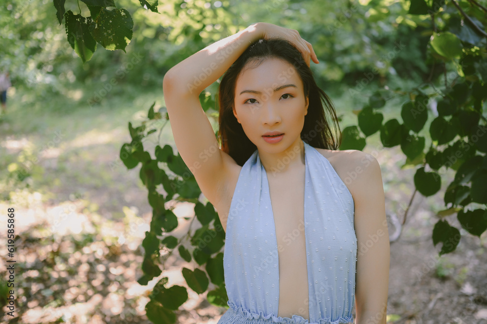 Close up outdoor portrait of Beautiful young happy Chinese Asian woman perfect skin posing outside sunny summer day green foliage. Natural facial treatment. Cosmetology, skin care and spa. Close up outdoor portrait of Beautiful young happy Chinese Asian woman perfect skin posing outside sunny summer day green foliage. Natural facial treatment. Cosmetology, skin care and spa.