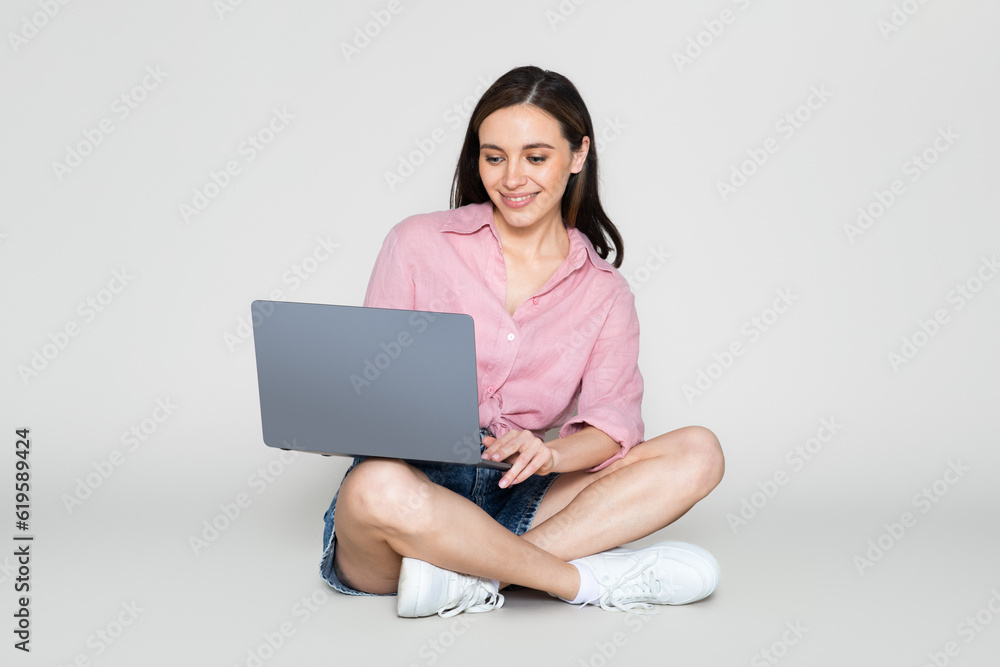 Happy pretty young woman using laptop, pastel background Happy pretty young woman using laptop, pastel background