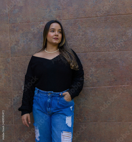 three quarter length image of a nice style young lady with nice makeup and long hair looking at something ahead a marble wall