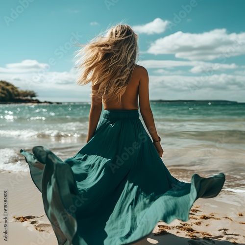 Standing on the beach, a blonde of exquisite beauty, clad in a green summer dress, revels in the panoramic ocean view. Backs turned.