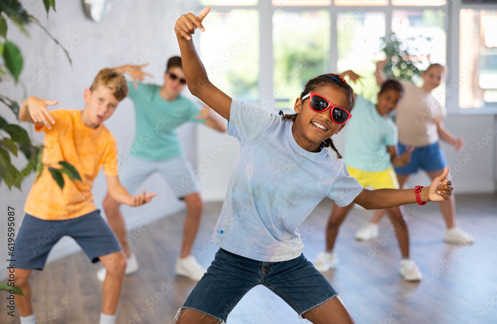 Obraz premium Positive boy exercising in group of classmates during dance class at school