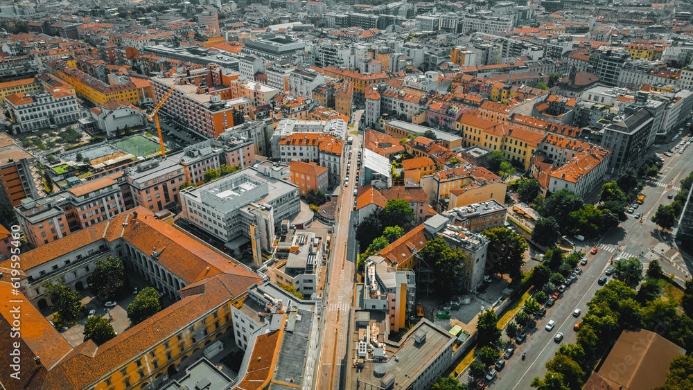 Aerial view of the roofs of buildings and city streets with cars and public transport. Classic and new architecture. Urban environment concept. Milan, Italy