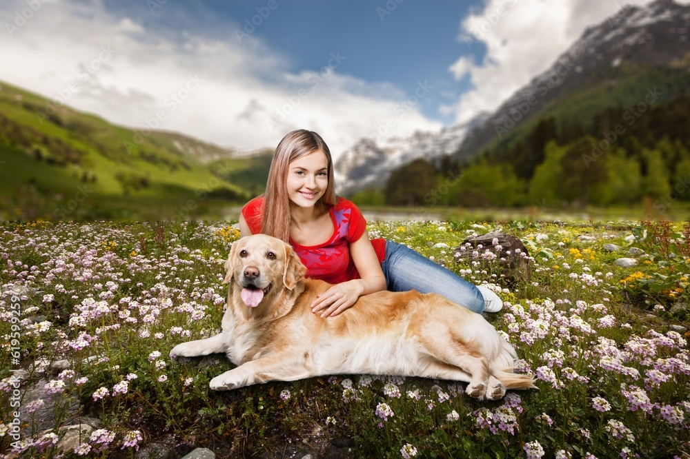 A young happy woman plays with cute dog on grass