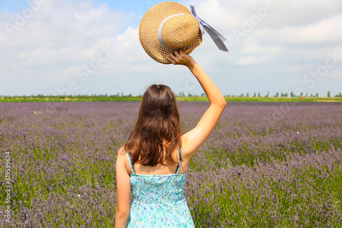 young girl with straw hat and short dress points in the middle of the lavender field in bloom photo