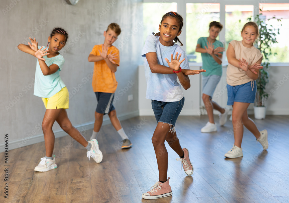 Fototapeta premium African man child dances waacking in choreographic school, group of young people in sportswear trains together with their classmates in gym before competitions, battle