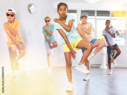 Portrait of cheerful african american preteen girl practicing hip-hop movements during group dance lesson in studio..