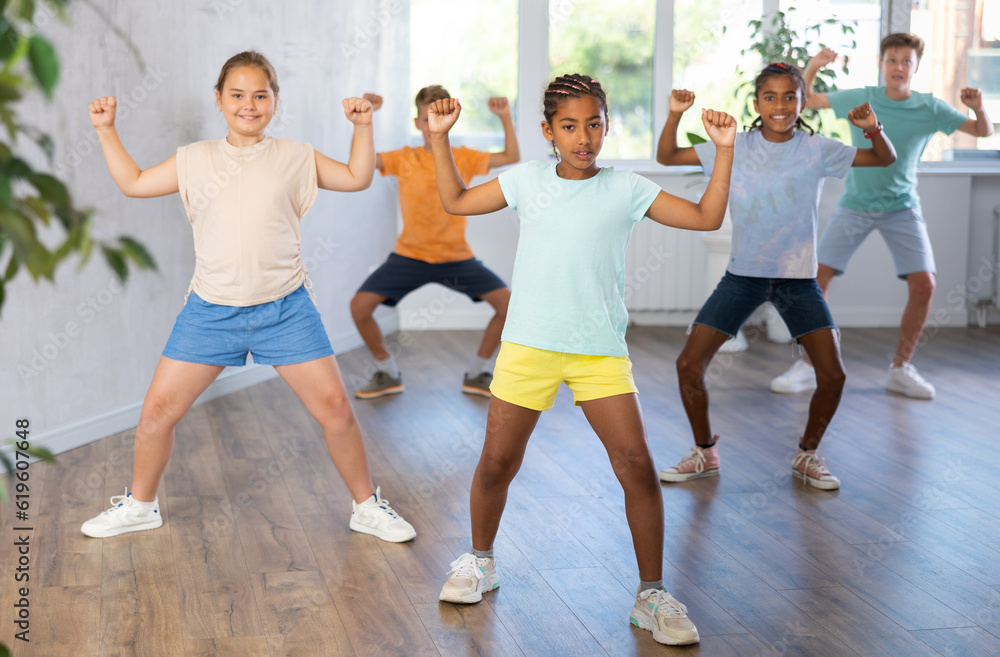 Confident dark-skinned tween girl krumper posing during workout in group dance class for children..