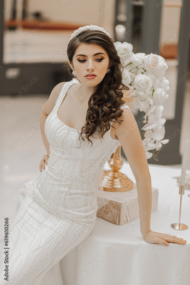 studio photo of a girl in a wedding dress, posing near a table with flowers studio photo of a girl in a wedding dress, posing near a table with flowers