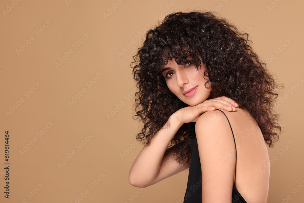 Beautiful young woman with long curly hair on beige background. Space for text Beautiful young woman with long curly hair on beige background. Space for text