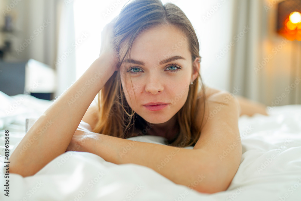 Portrait of woman lying on bed and looking at camera at home Portrait of woman lying on bed and looking at camera at home