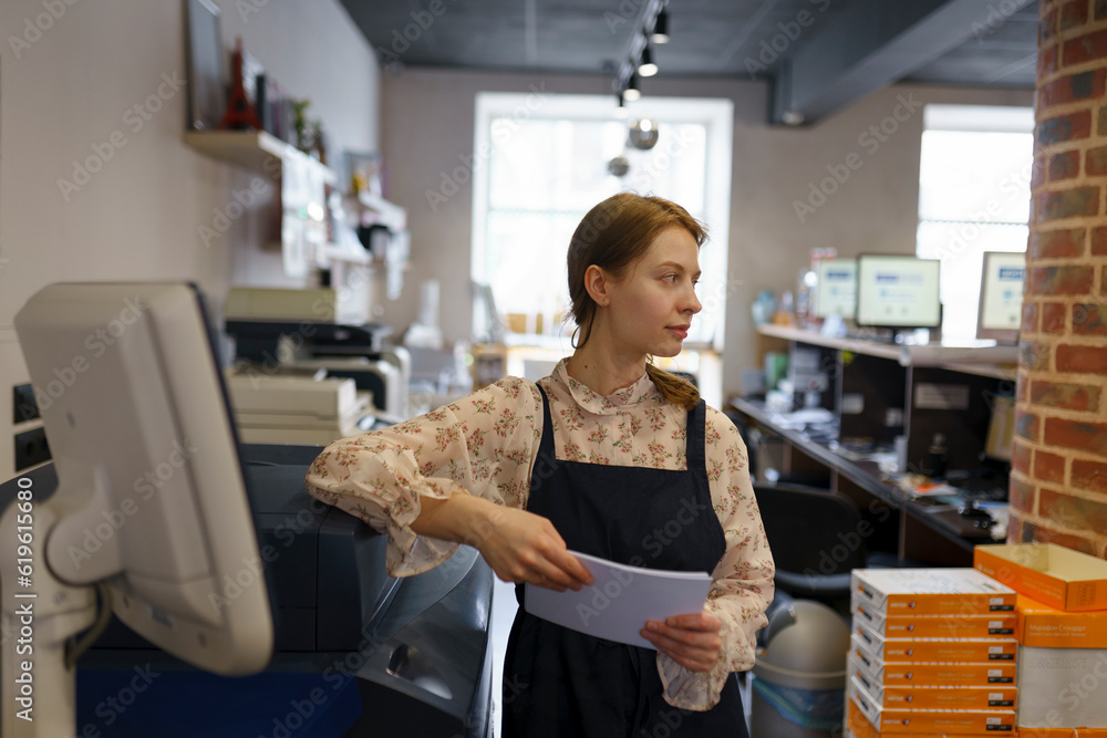 Woman holding paper while working in printing plant Woman holding paper while working in printing plant