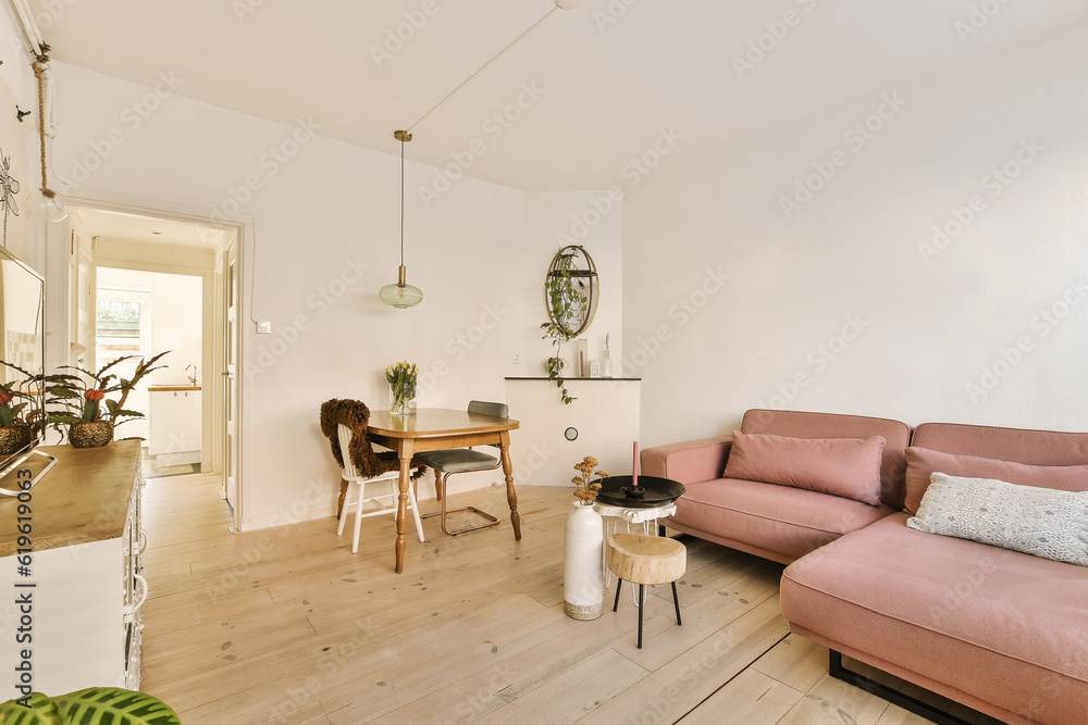 Fototapeta premium a living room with a pink couch and some plants on the table in front of the couch is an open door