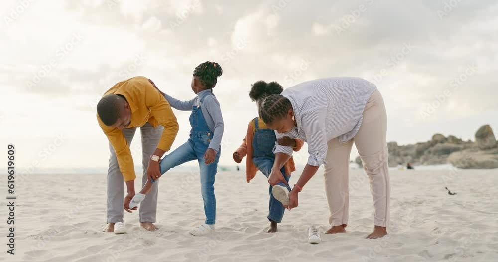 Summer, sand and a black family at the beach with shoes for walking or running together. Happy, travel and African children with parents getting ready for playing by the sea during a holiday Summer, sand and a black family at the beach with shoes for walking or running together. Happy, travel and African children with parents getting ready for playing by the sea during a holiday