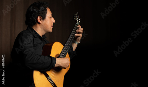 hispanic man playing guitar  guitarist on a black background studio shot  latin professional guitar player