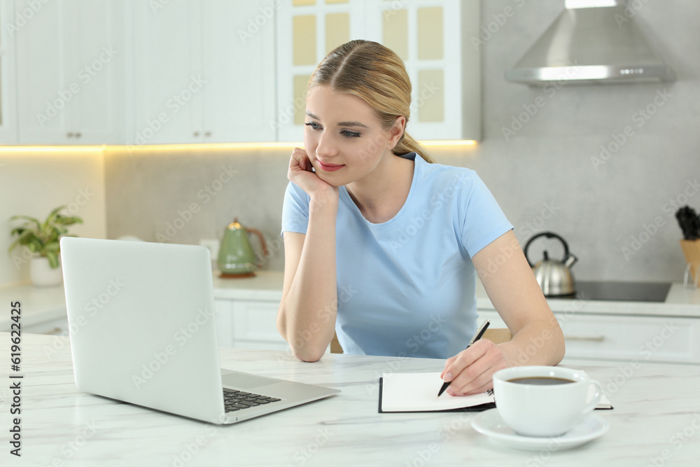 Home workplace. Woman working on laptop at marble desk in kitchen Home workplace. Woman working on laptop at marble desk in kitchen