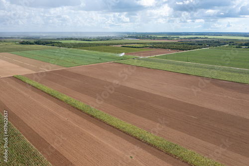Aerial view of planted and unplanted agricultural fields and irrigation in Homestaed, Florida under summer cloudscape.