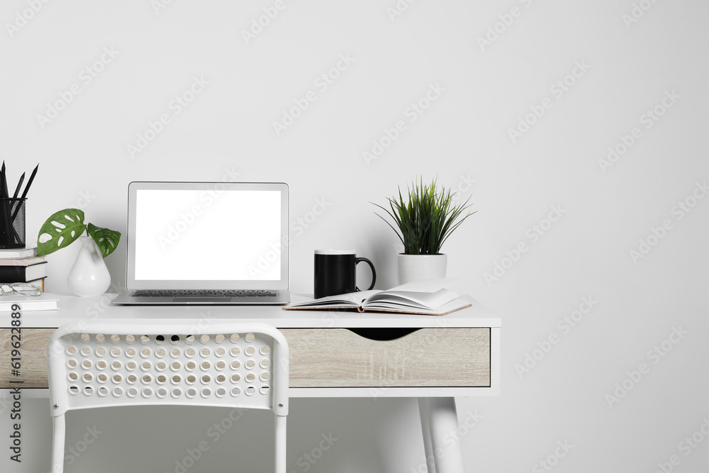 Cozy workspace with laptop, houseplants and stationery on wooden desk at home Cozy workspace with laptop, houseplants and stationery on wooden desk at home