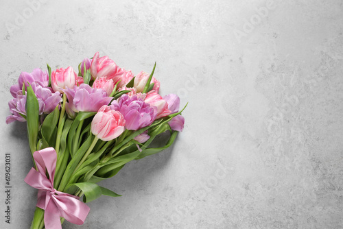 Beautiful bouquet of colorful tulip flowers on light gray table, top view. Space for text
