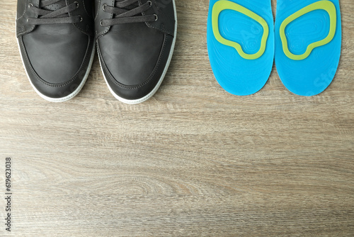 Orthopedic insoles near shoes on floor, flat lay. Space for text