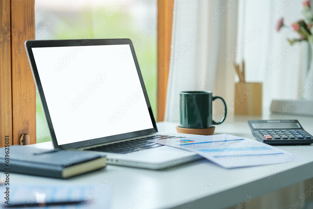 Laptop computer with empty screen, stationery and potted plant on white table in bright office. Laptop computer with empty screen, stationery and potted plant on white table in bright office.