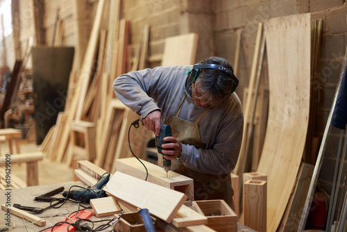 Ageless Skills: Seasoned Artisan Operating a Drill in a Woodworking Studio